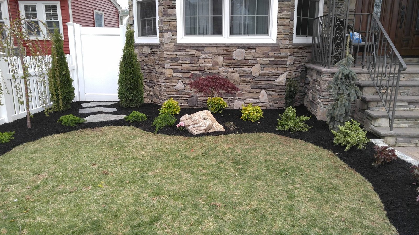 Luxury Long Island landscaping with layered plantings and stonework.